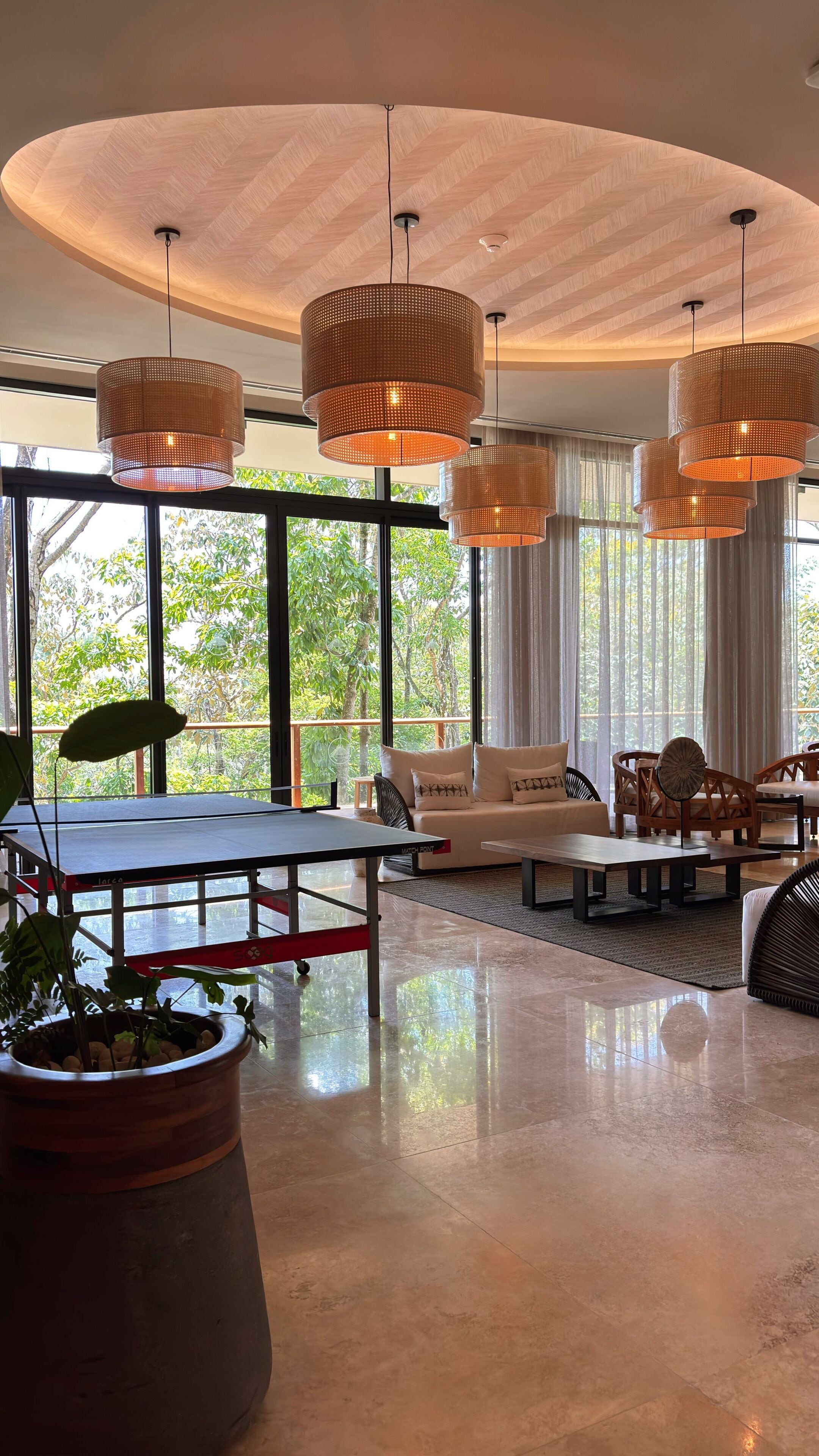 A modern interior with large windows, a round ceiling, and multiple hanging pendant lights.
