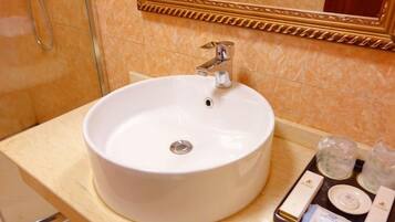 A white bathroom sink with a single faucet, a mirror above it, and a tray with toiletries.