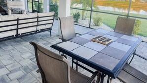 A patio area with a table and chairs, a sofa, and a view of a water body and palm trees. - Welcome to Punta Paradise! Book Now! (Punta Gorda)