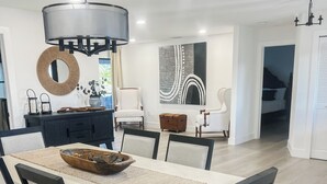 A modern dining area with a white table, black chairs, and a central light fixture. - Welcome to Punta Paradise! Book Now! (Punta Gorda)