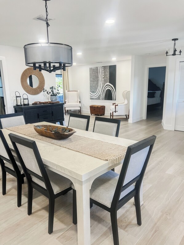 A modern dining area with a white table, black chairs, and a central light fixture. - Welcome to Punta Paradise! Book Now! (Punta Gorda)