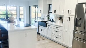 A modern kitchen with white cabinetry, a stainless steel refrigerator, and a large island. - Welcome to Punta Paradise! Book Now! (Punta Gorda)