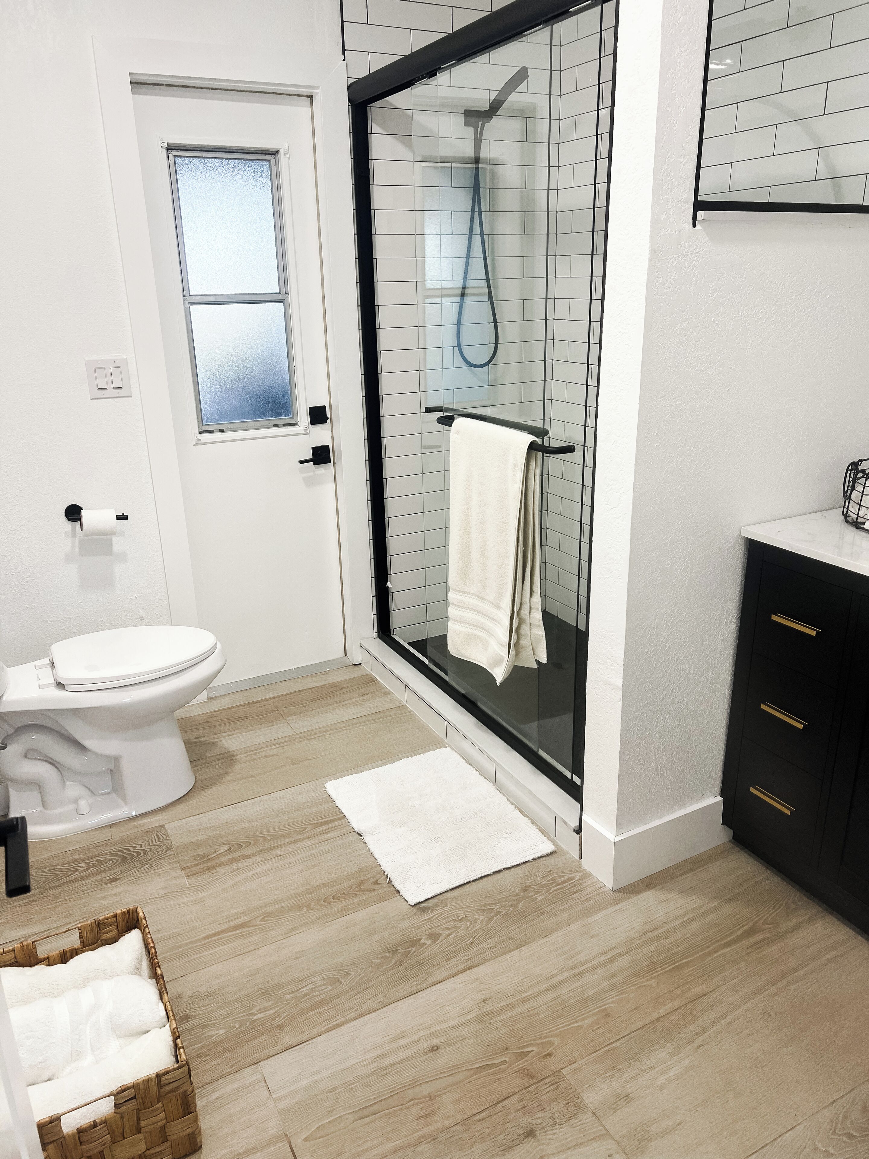 Een moderne badkamer met een douchecabine van glas, een toilet en een wastafel met lades.