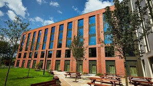 A modern building with a brick facade, large windows, and outdoor seating areas. - Student Only Vita Pebble Mill (Birmingham)