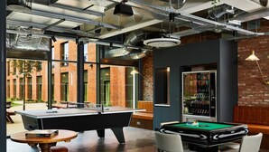 A billiards table, a pool table, and a bar area with a refrigerator and drinks. - Student Only Vita Pebble Mill (Birmingham)
