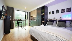 A modern bedroom with a large bed, a desk, and a view of the outdoors. - Student Only Vita Pebble Mill (Birmingham)