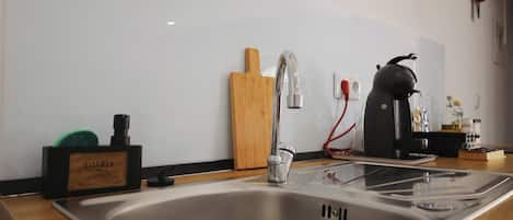 A modern kitchen with a stainless steel sink, a kettle, and a cutting board.