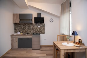 A modern kitchen with wooden cabinets, a built-in microwave, and a stainless steel refrigerator. - Velora Apartments (Subotica)