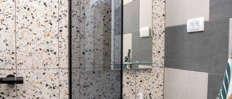 A modern bathroom with a glass shower enclosure, a white sink, and a mirror.