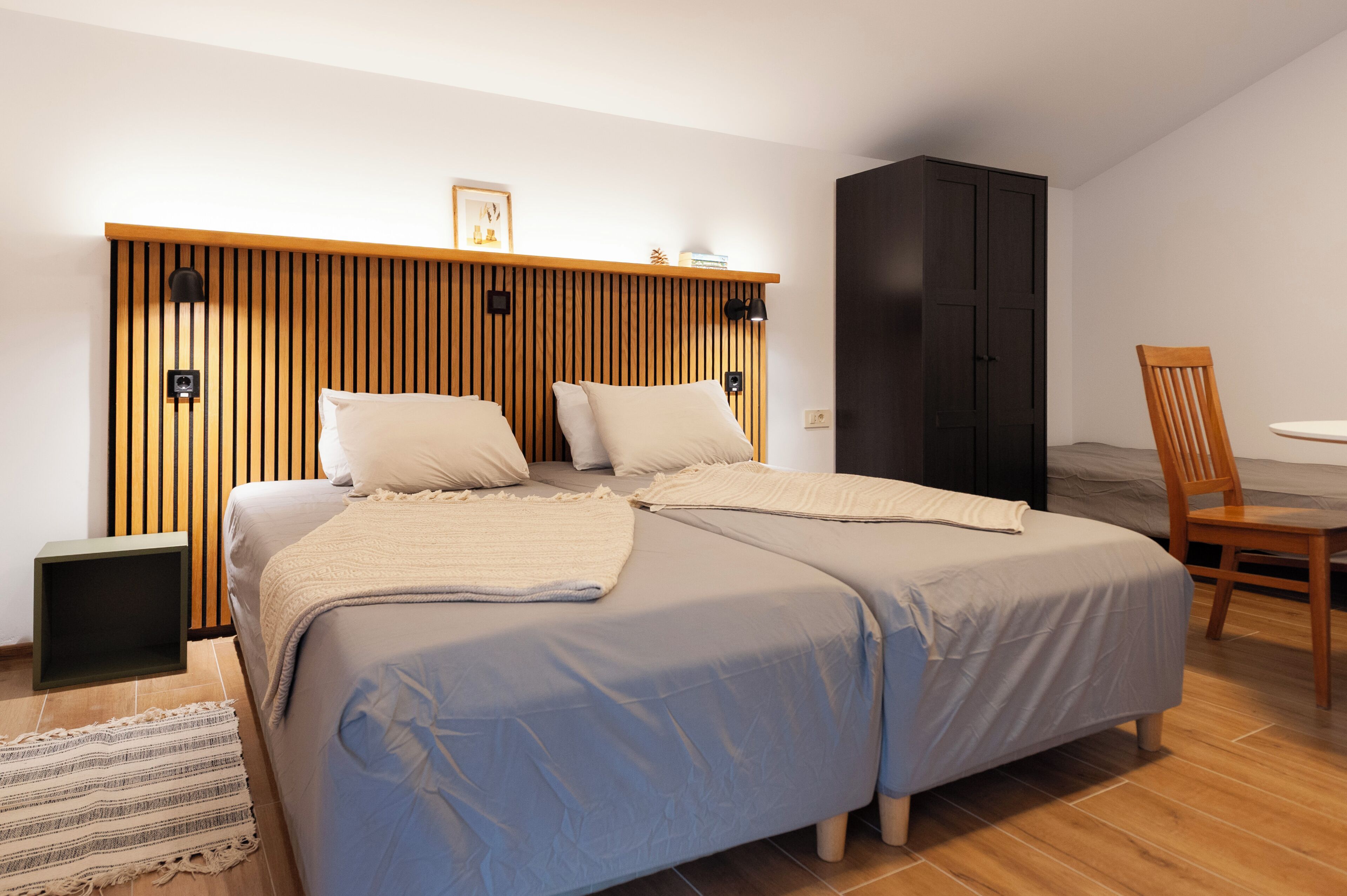 A bedroom with a bed, bedside tables, a wardrobe, and a chair.