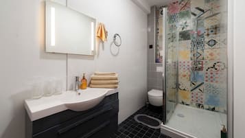 A modern bathroom with a white vanity, a glass shower enclosure, and a toilet.