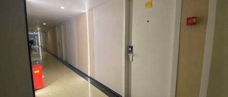 En gang med en dør, en brandalarm og en rød genstand på gulvet.
