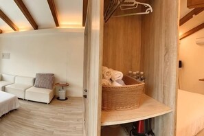 A room with a white sofa, a small table, a wicker basket with towels, and a wooden wall.