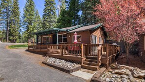 Une cabane dotée d’une véranda, d’une terrasse en bois et d’un petit espace extérieur aménagé pour s’asseoir.