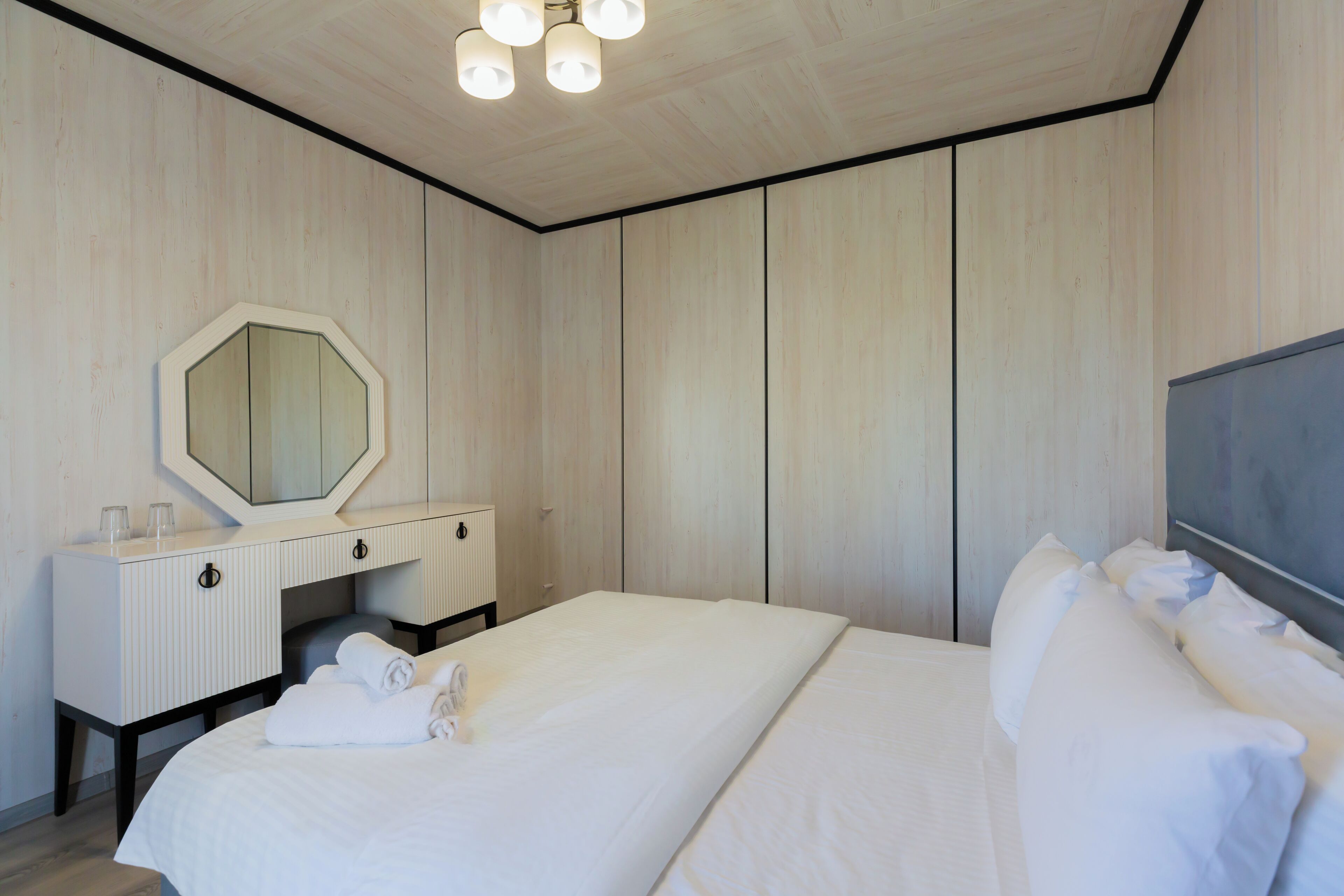Una camera d'albergo con un letto grande, un comodino con uno specchio e un armadio.