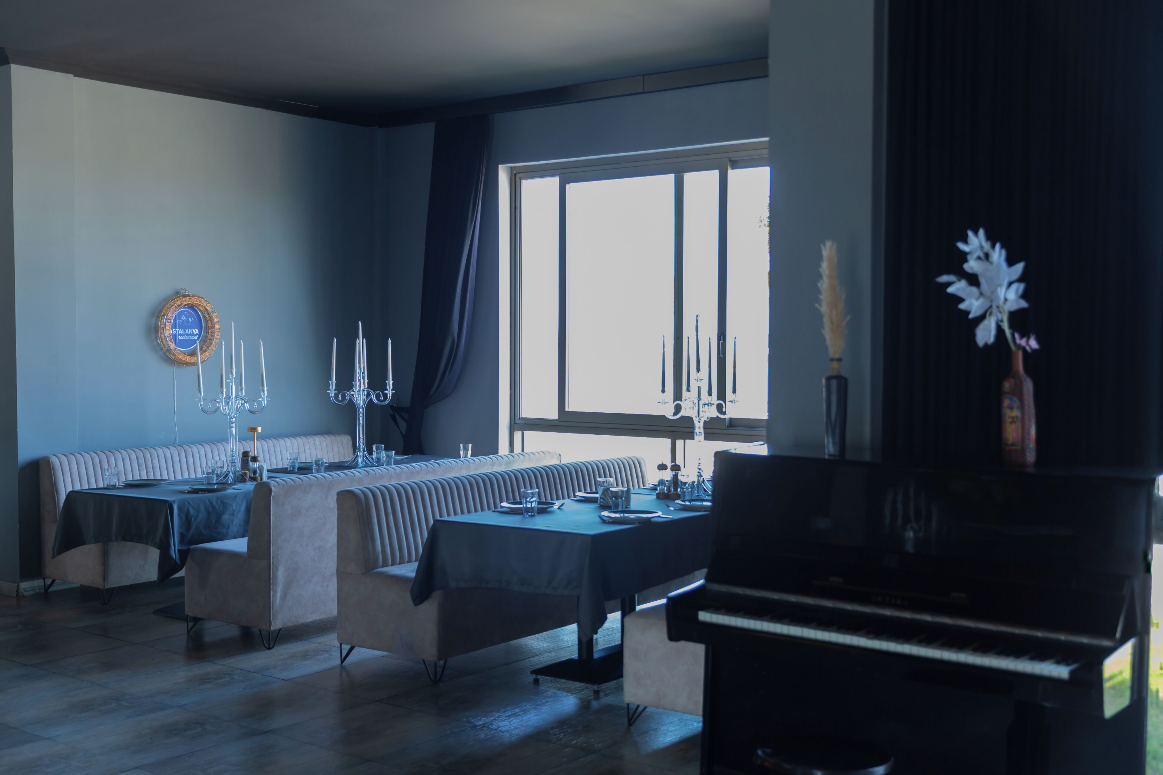 A dining area with a long table, chairs, and a piano.