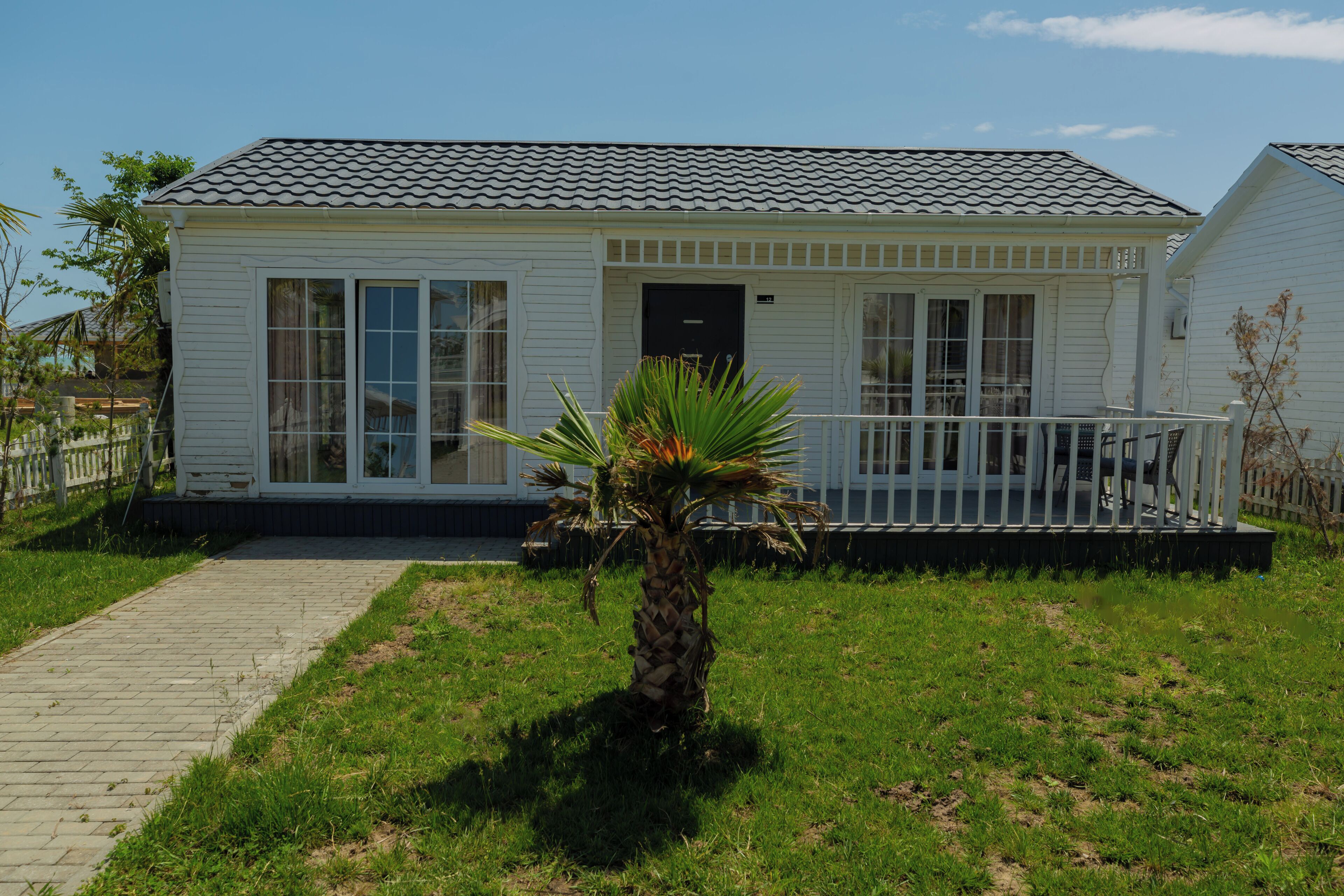 A single-story white building with a tiled roof, large windows, and a small porch with a railing.