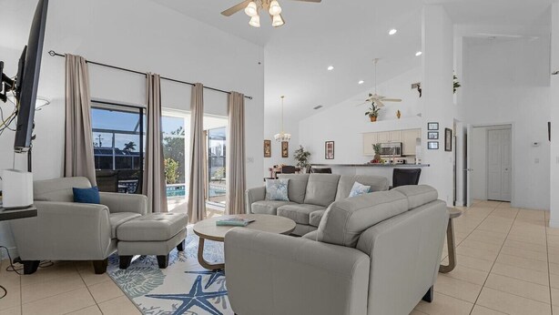 Un salón amplio con un sofá grande, una mesa de centro y un televisor. Cuenta con un balcón con vistas al exterior.