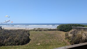 Una spiaggia con cielo sereno, una passerella in legno e una zona verde.