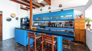 A modern kitchen with blue cabinets, a black countertop, and a central island with two chairs. - Beachfront AC Villa, 3BR, 3.5BA,  great surfing! Free Parking (Guanacaste Province)
