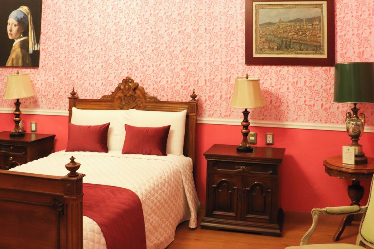 A bedroom with a wooden bed, two nightstands, a chair, and a lamp.