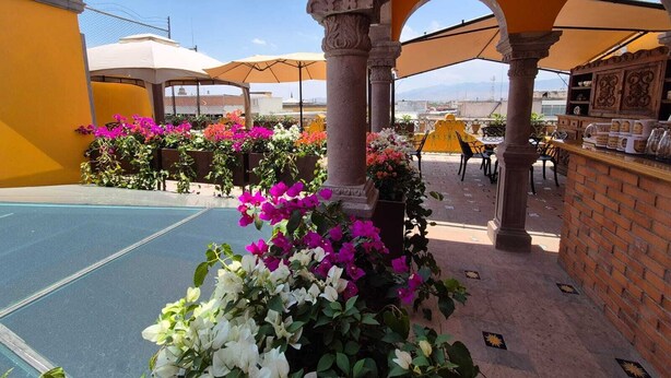 A rooftop terrace with a pool, outdoor seating, and a bar area.
