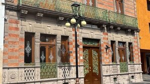 A historic building with ornate architectural details, including decorative iron railings and a prominent entrance with a wooden door.