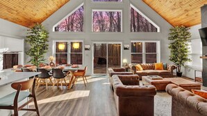 Amplia sala de estar con techo alto, ventanas grandes y comedor con muebles modernos.