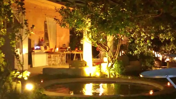 Spazio esterno serale con piscina, posti a sedere e zona pranzo con tavoli e sedie.