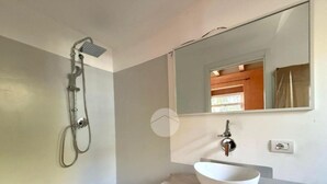 Un bagno con doccia, lavandino e specchio.