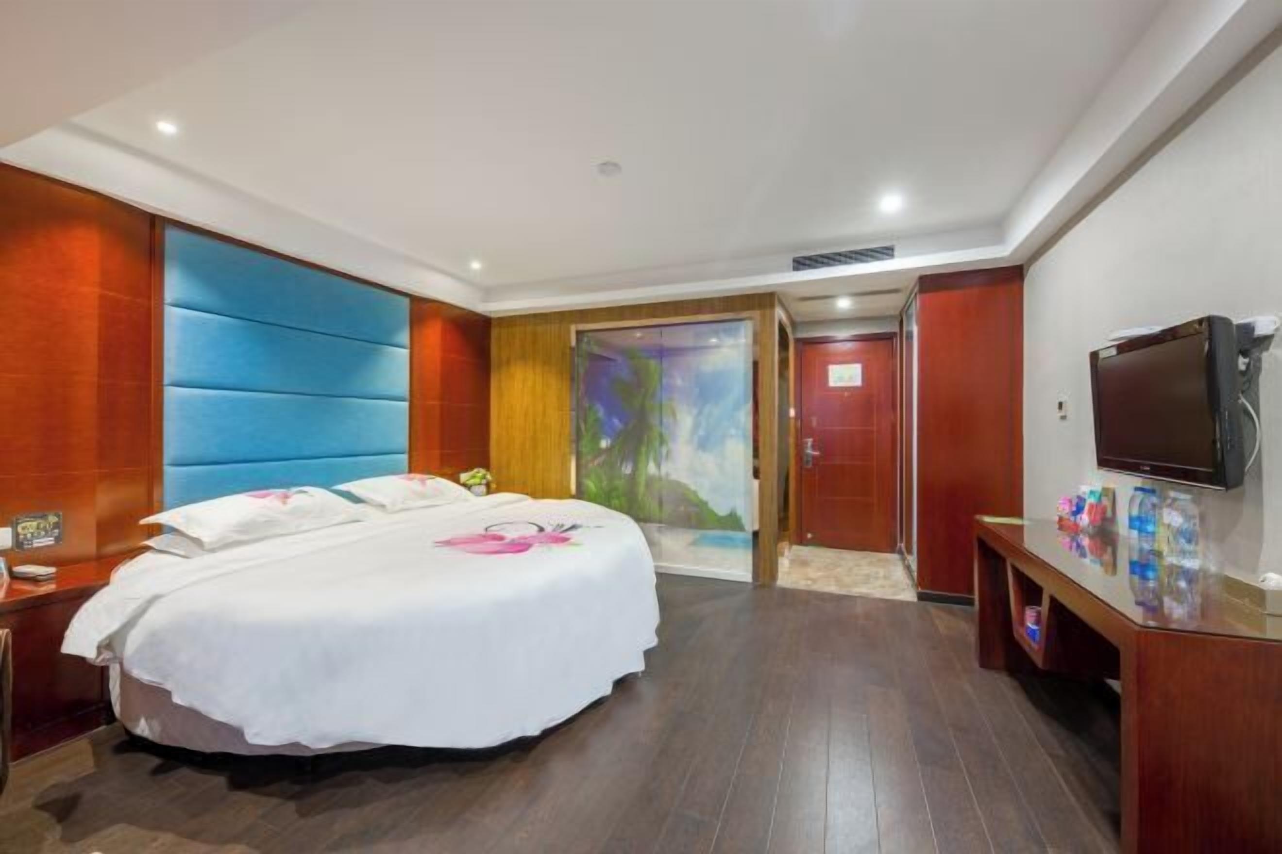 A hotel room with a large bed, a TV, and a wooden cabinet.