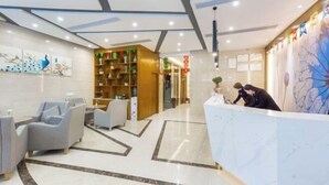 A modern hotel lobby with a reception desk, seating area, and a decorative wall. - Jinteng Hotel (Yiwu)