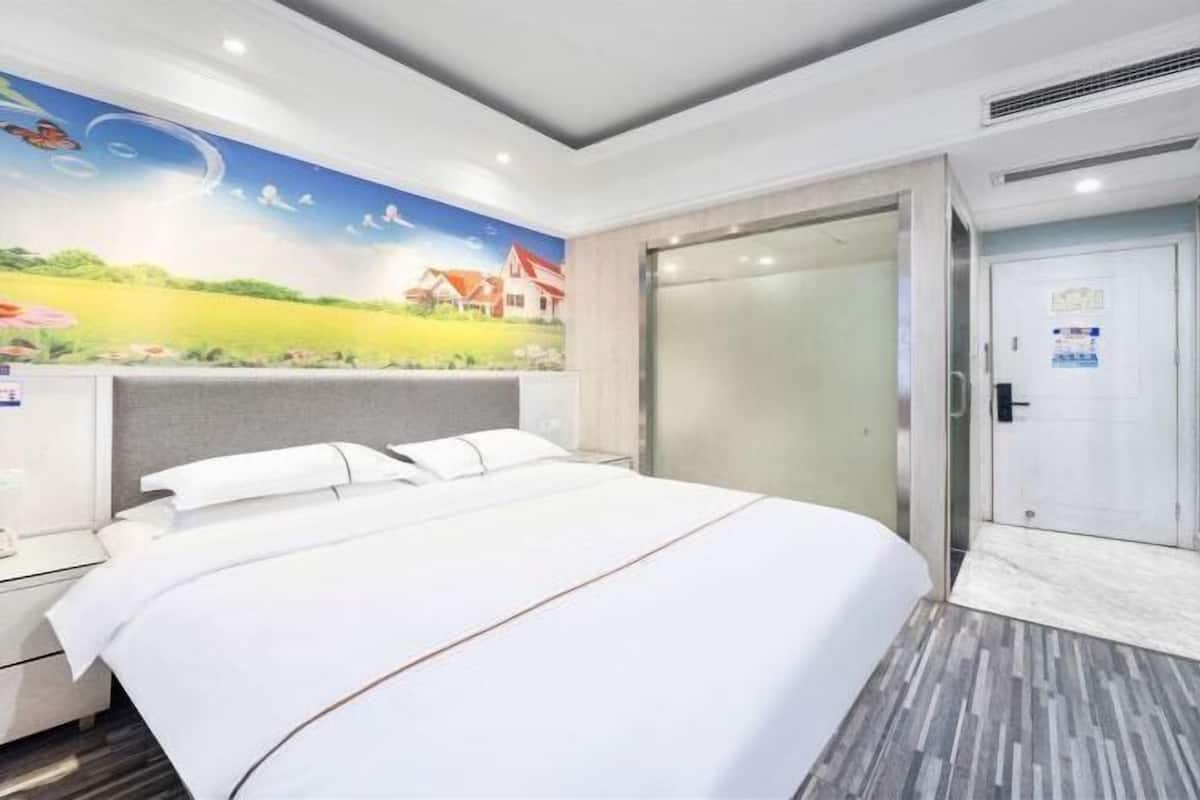 A hotel room with a bed, a nightstand, a wall mural, a sliding door, and a tiled floor.
