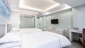 A hotel room with a large bed, a desk, a television, and a shower area. - Jinteng Hotel (Yiwu)