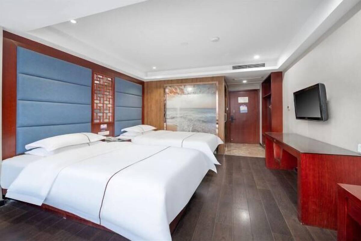 A hotel room with two beds, a TV, and a reception desk.
