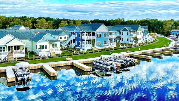 Een pand aan het water met meerdere huizen, een steiger en boten.