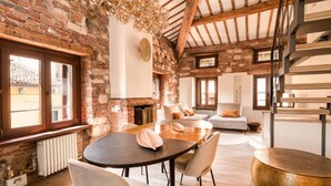 A rustic dining area with exposed brick walls, a wooden ceiling, and a round table with chairs. - River Cross ✔ Self Check-In (Verona)