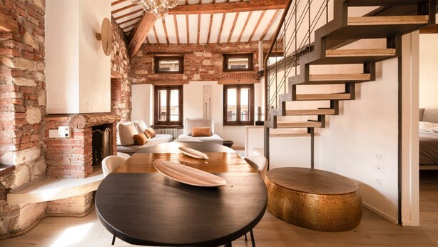 A modern interior with exposed brick walls, a wooden dining table, and a staircase with a minimalist design. - River Cross ✔ Self Check-In (Verona)