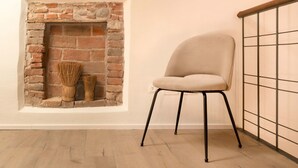 A room with a brick fireplace, a beige chair, and a wooden floor. - River Cross ✔ Self Check-In (Verona)