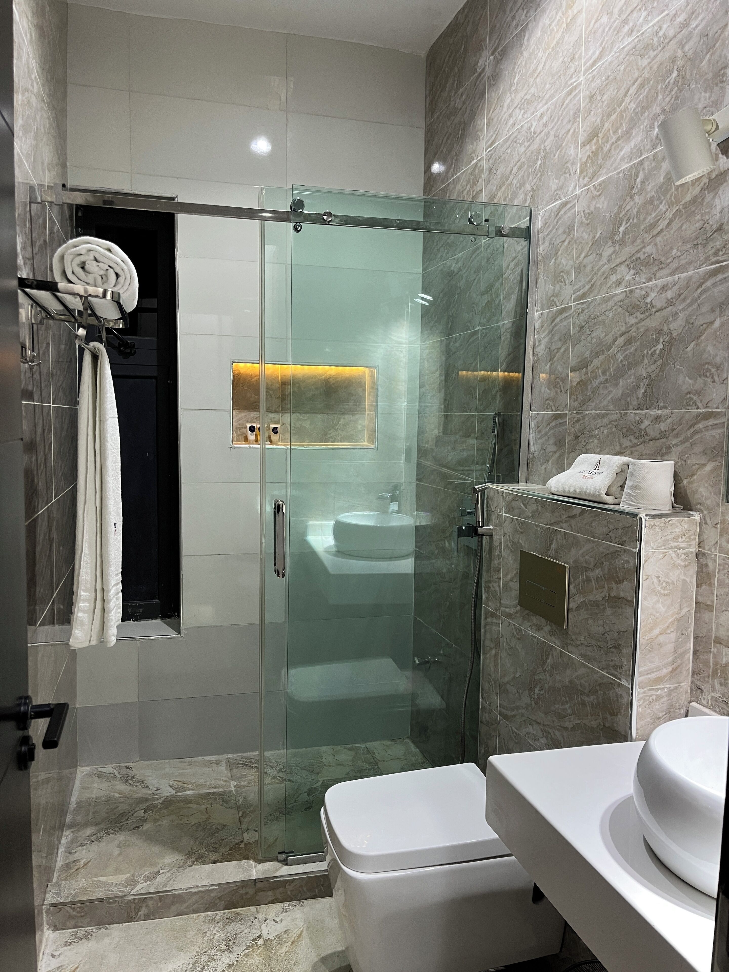 Ein modernes Badezimmer mit einer gläsernen Dusche, einer weißen Toilette und einem Waschtisch.