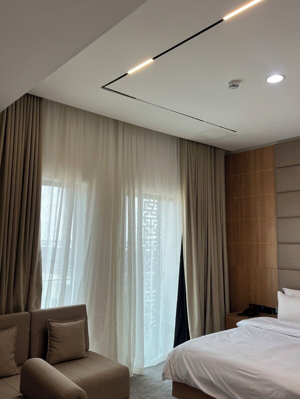 A modern hotel room with a large bed, a sofa, and a desk.
