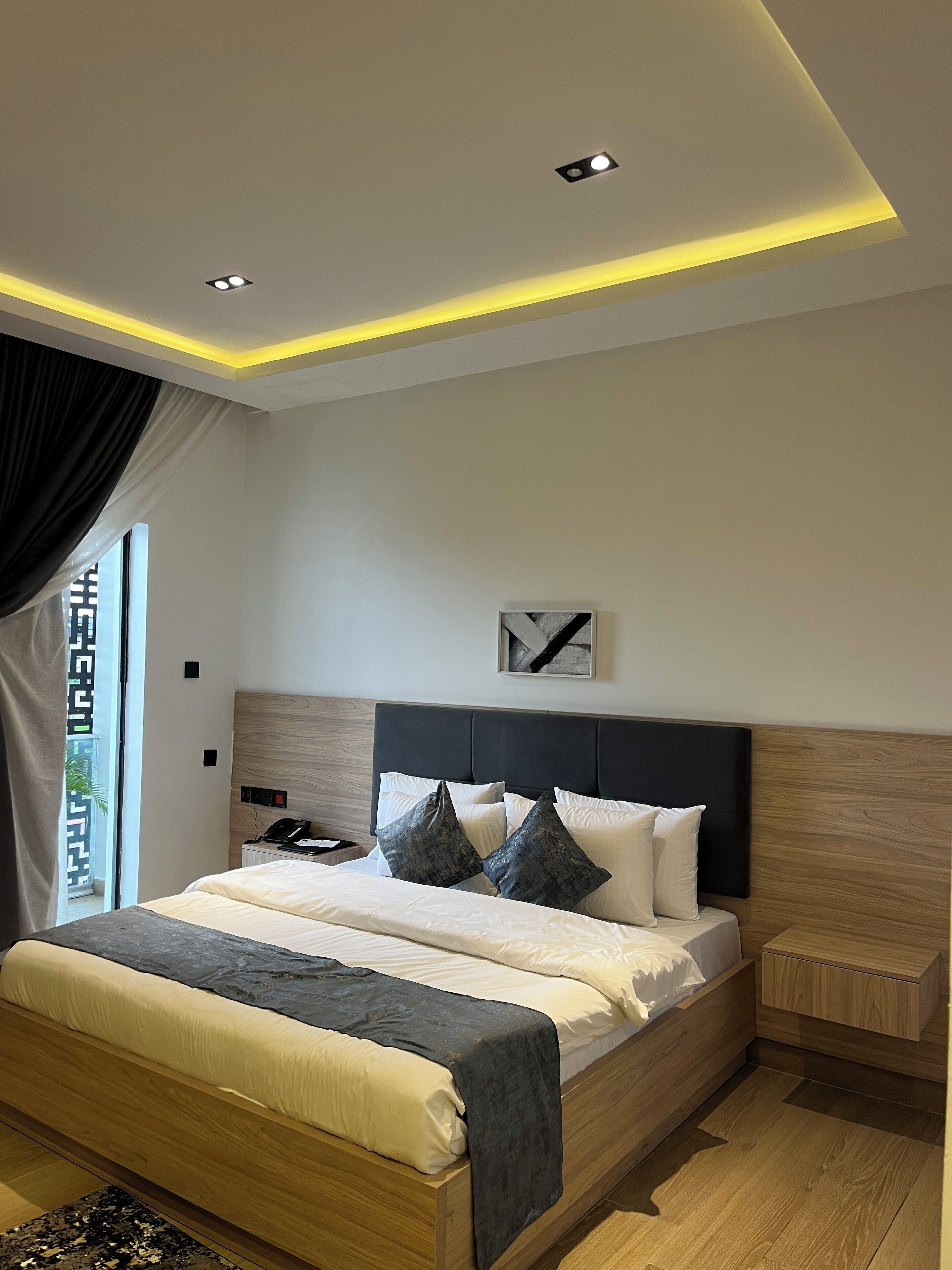 A modern bedroom with a wooden bed, a nightstand, and a ceiling light fixture.