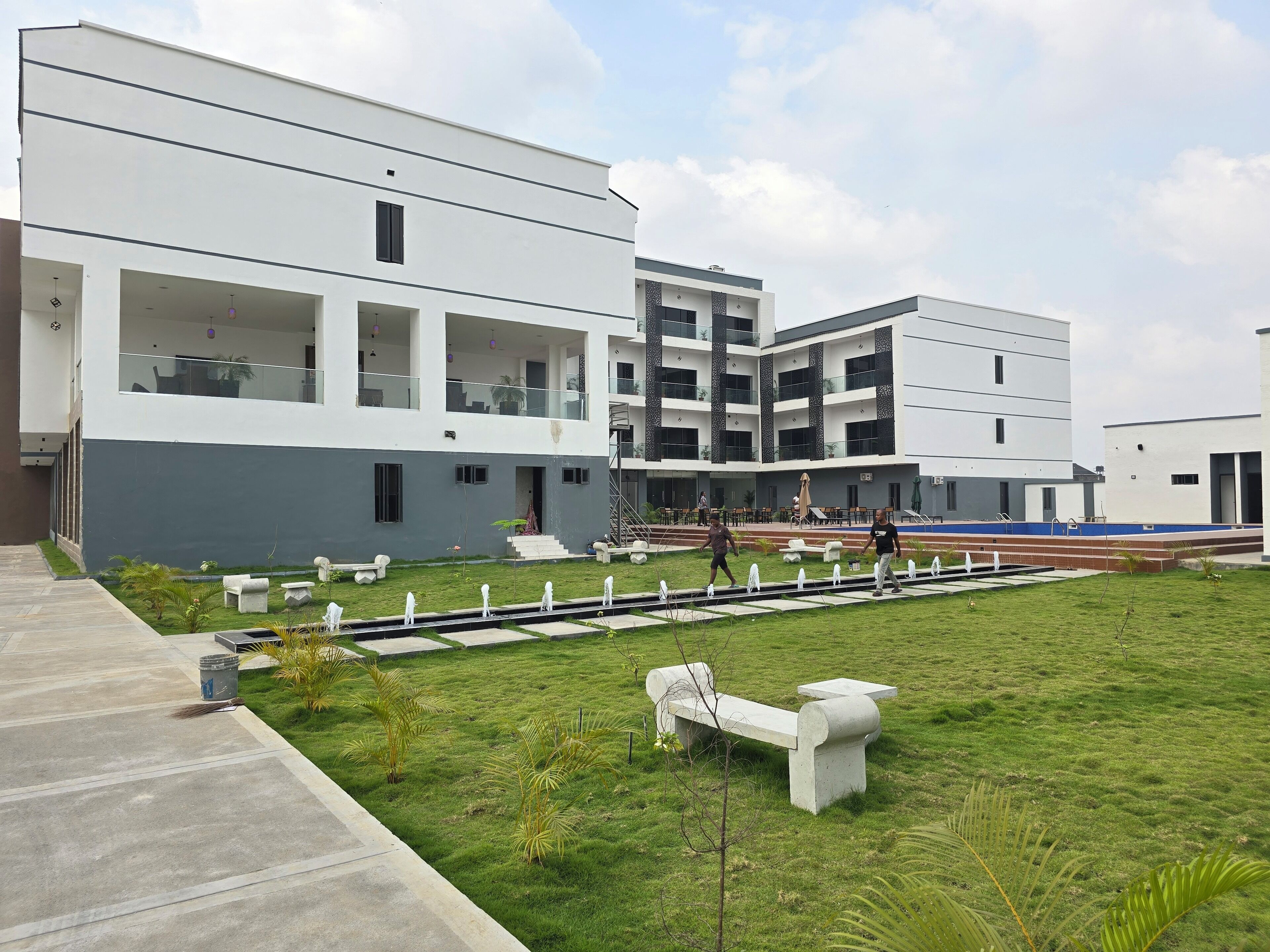 A modern building with multiple floors, outdoor seating areas, and a well-maintained lawn.
