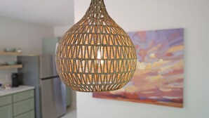 Luminária trançada pendurada em uma cozinha com um quadro abstrato e colorido na parede.