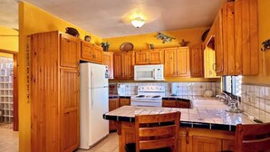 A kitchen with wooden cabinets, a refrigerator, a microwave, and a stove.