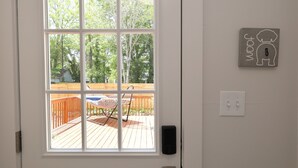 Una puerta blanca con ventanal, una terraza de madera y un interruptor de luz en la pared.