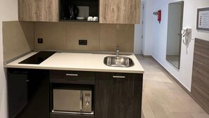 A compact kitchen with a built-in microwave, a sink, and a dishwasher. - Purple 4: Studio Apartment in St. Julian's (Swieqi)