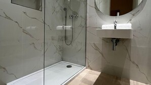 A modern bathroom with a glass-enclosed shower, a sink with a mirror, and marble walls. - Purple 4: Studio Apartment in St. Julian's (Swieqi)