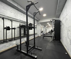 A gym with weightlifting equipment, mirrors, and a bench. - Orange 8: Studio Apartment in St. Julian's (Swieqi)