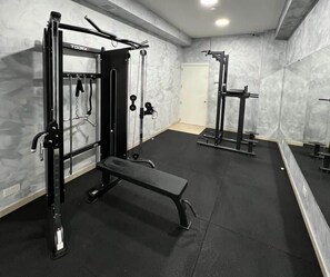 Un gimnasio con una jaula para sentadillas, un banco de pesas y un banco.
